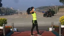 مروحيات فوقها ومدرعات وراءها وهي بعالم آخر! فيديو يجتاح مواقع التواصل لفتاة تقوم برياضتها الصباحية قرب برلمان ميانمار لحظة الإنقلاب العسكري